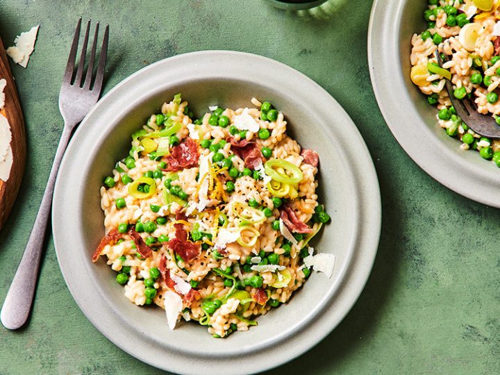 Risotto met doperwten, prei en parmaham in een grijze kom