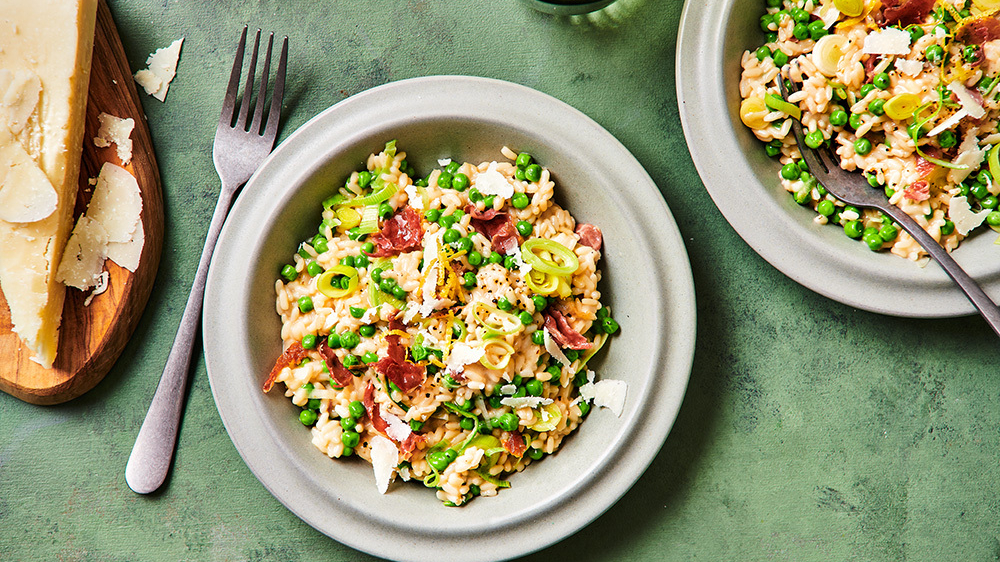 Risotto met doperwten, prei en parmaham in een grijze kom